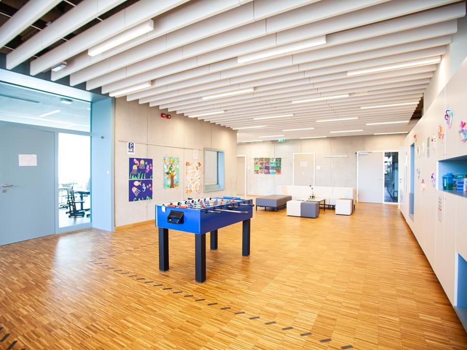 Rows of free-hanging, acoustic ceiling panels in school multifunctional area