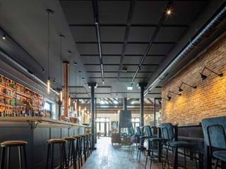Glued acoustic ceiling in hotel bar with brick wall