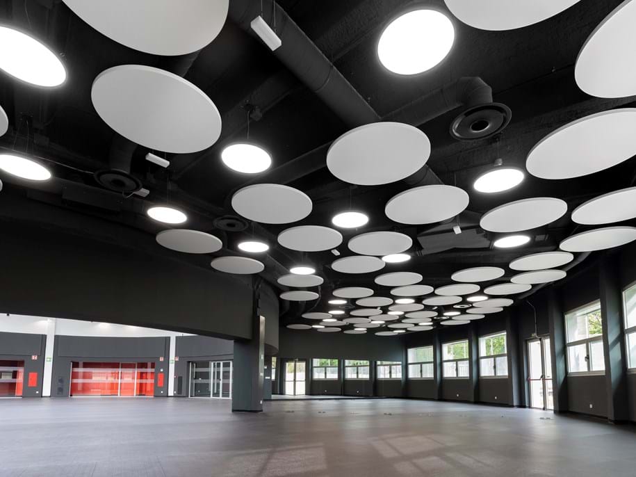 Round, free-hanging acoustic panels in sports hall entrance area
