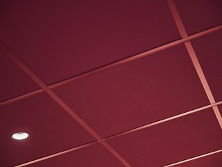 Close-up of dark red suspended acoustic ceiling with matching grids