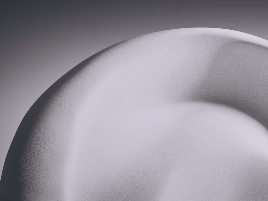 Close-up view of a white, textured surface with soft undulating curves and subtle shadows, giving the impression of a smooth, sculpted object.