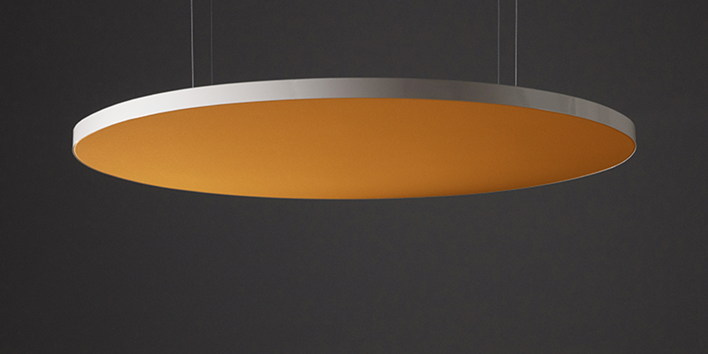 Un panneau acoustique moderne, circulaire, orange et argent, est suspendu par de fins câbles sur un fond sombre. La face inférieure est orange, contrastant avec le bord argenté élégant.